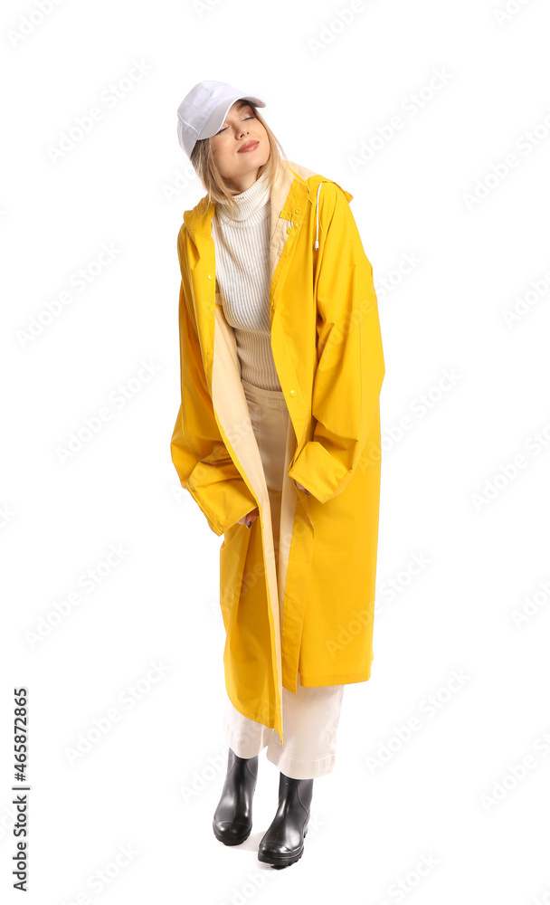 Young woman in yellow coat and baseball cap on white background