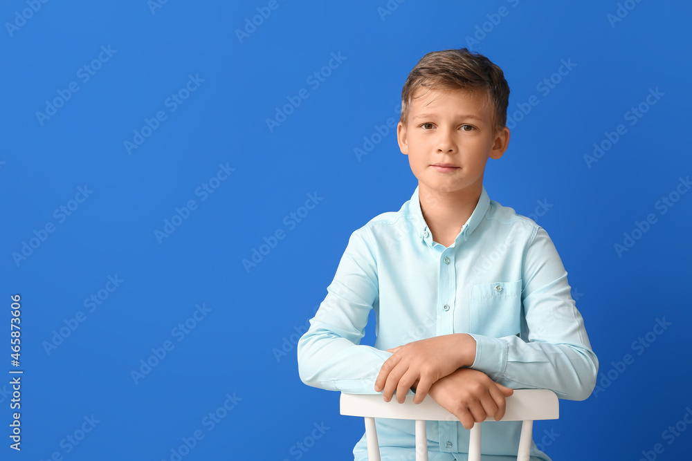 Little boy sitting on chair against blue background