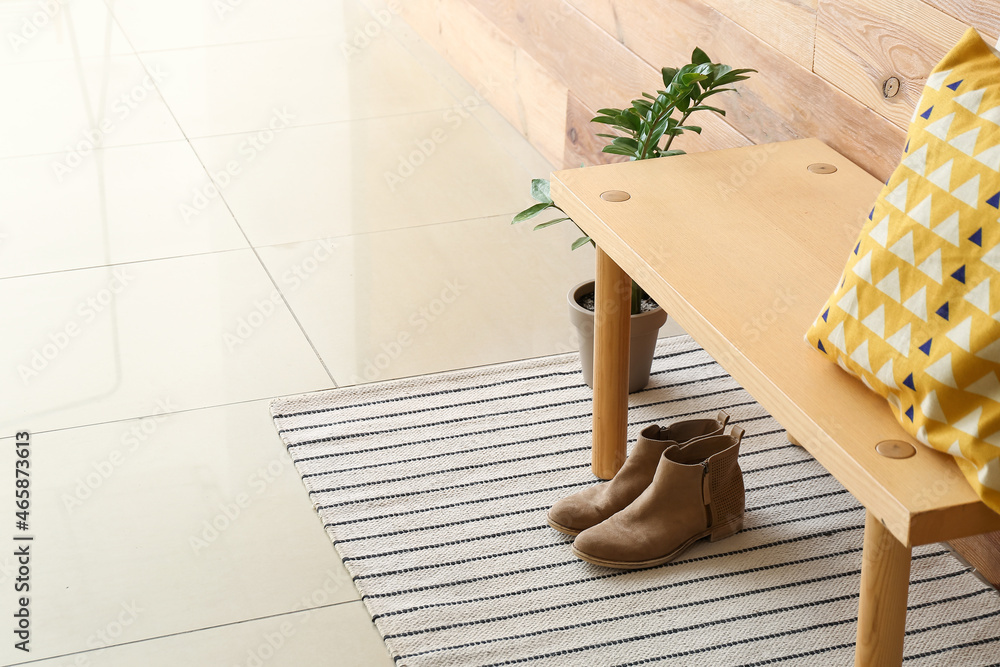 Bench with female shoes and houseplant near wooden wall