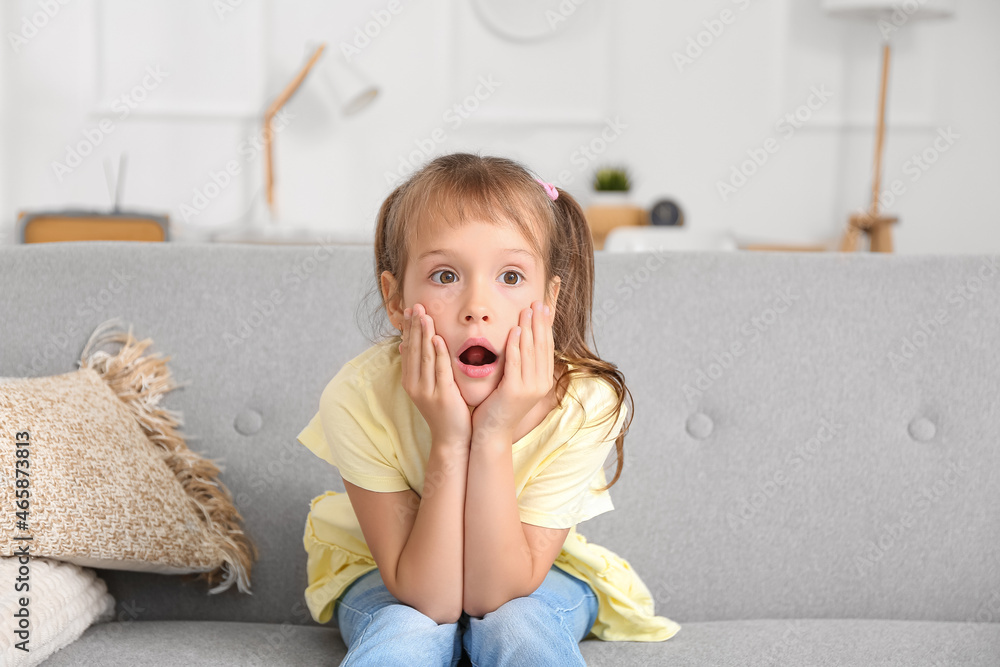 Surprised little girl watching TV at home