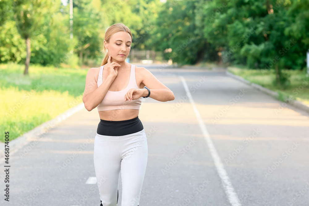 Female runner checking pulse outdoors