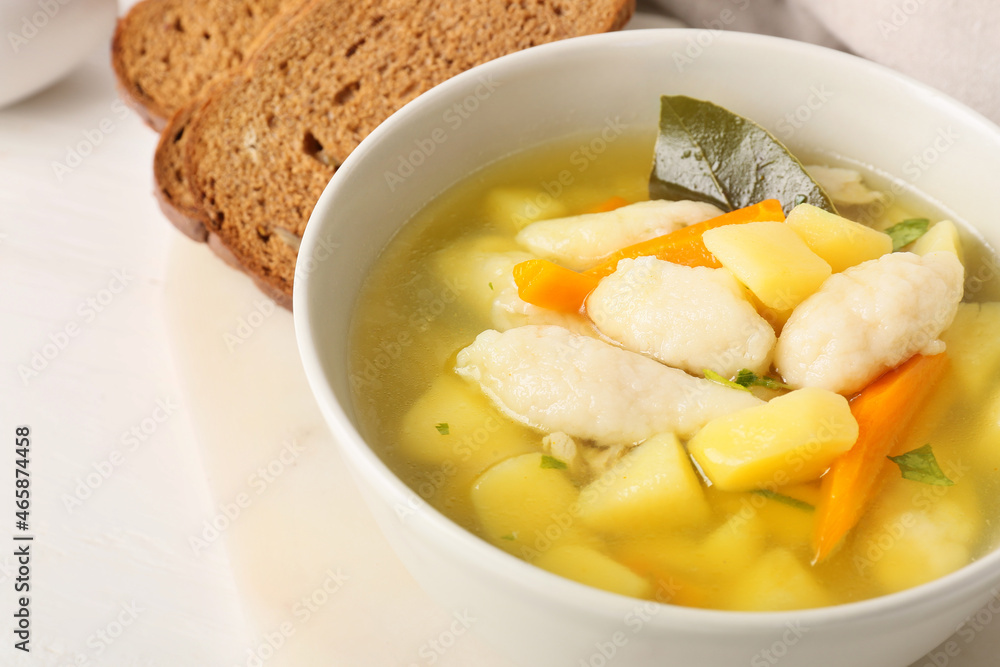 Bowl of tasty dumpling soup on light background, closeup