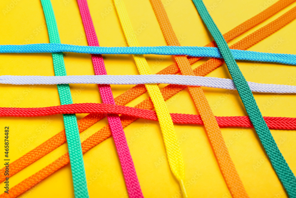 Colorful shoe laces on yellow background, closeup