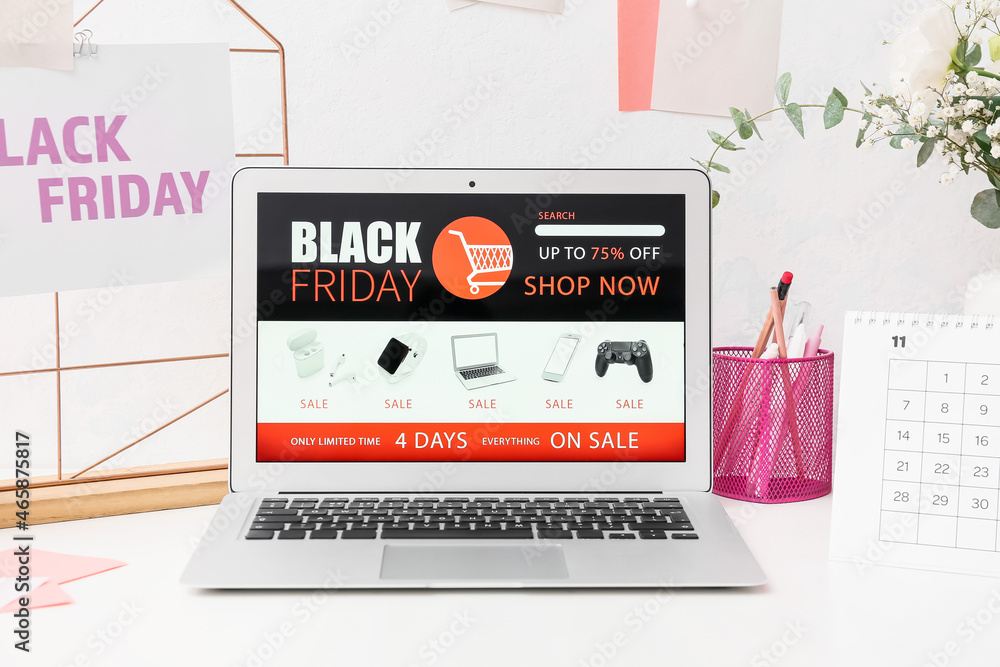 Laptop with open page of online store on table. Black Friday