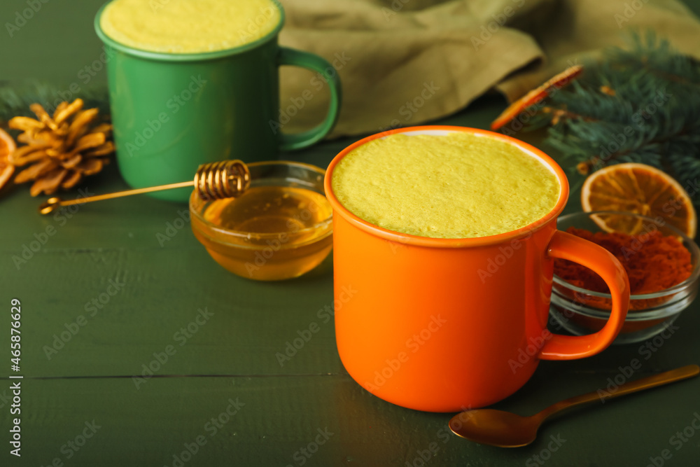 Cup of tasty turmeric latte with honey on color wooden background