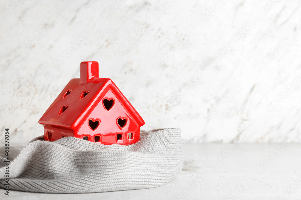 House figure with grey scarf on light background. Winter concept