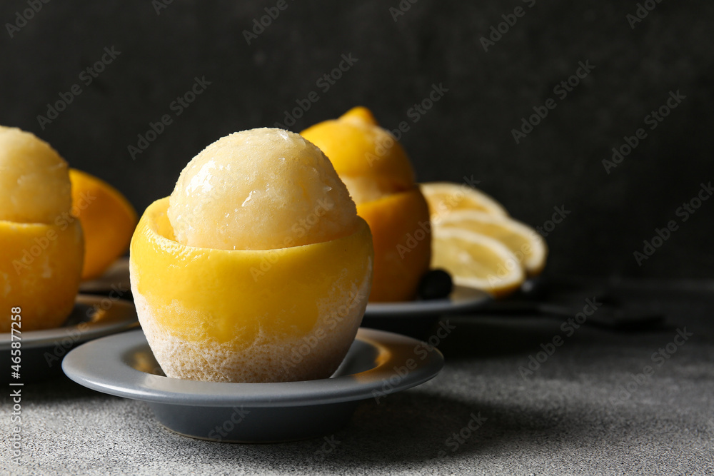 Plates with tasty ice creams in lemon peels on dark background