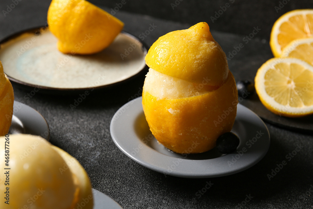 Plates with tasty ice creams in lemon peels on dark background