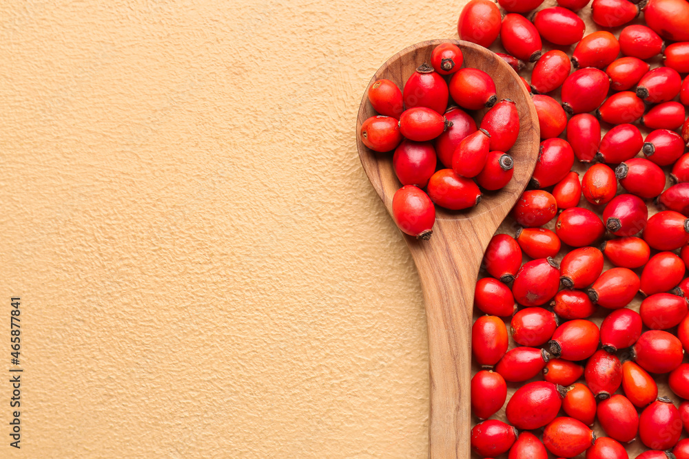 Fresh rose hip berries and spoon on beige background, closeup