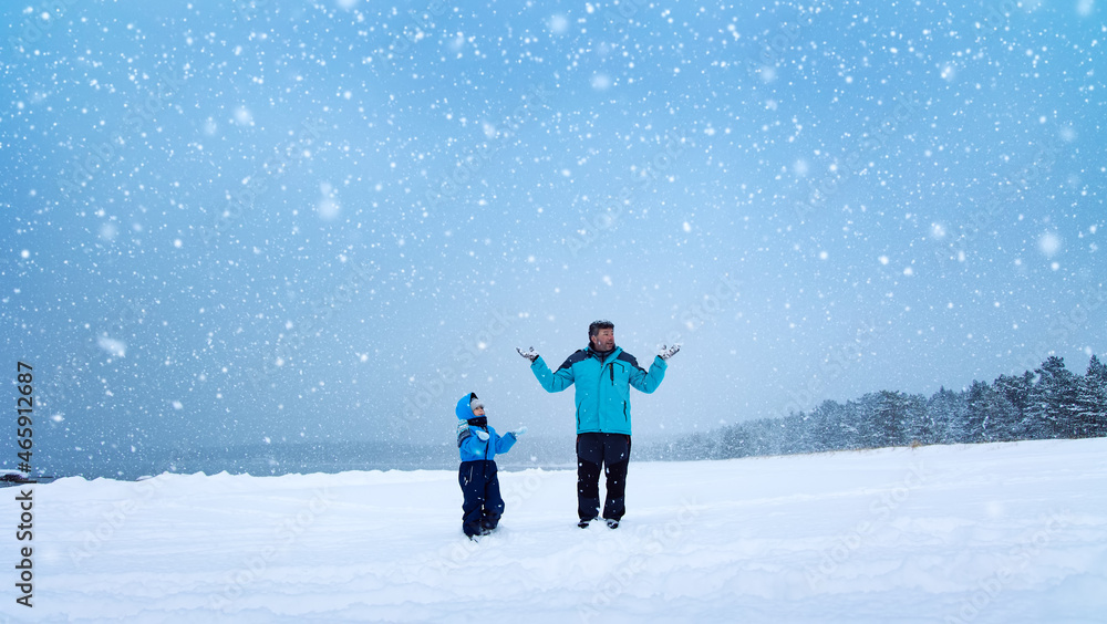 父亲和儿子站在白雪皑皑的冬季森林里的雪地上