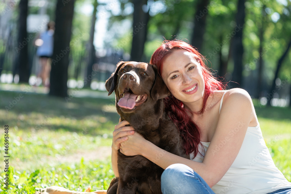 Young attractive woman hugs her dog in the park.