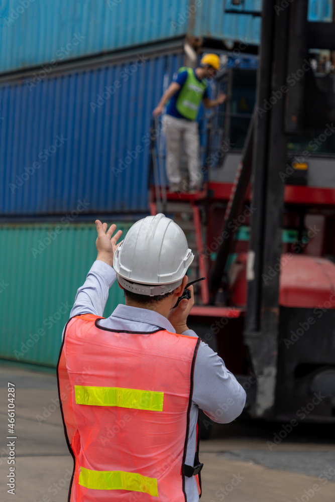 Industrial worker works with co-worker at overseas shipping container yard . Logistics supply chain 