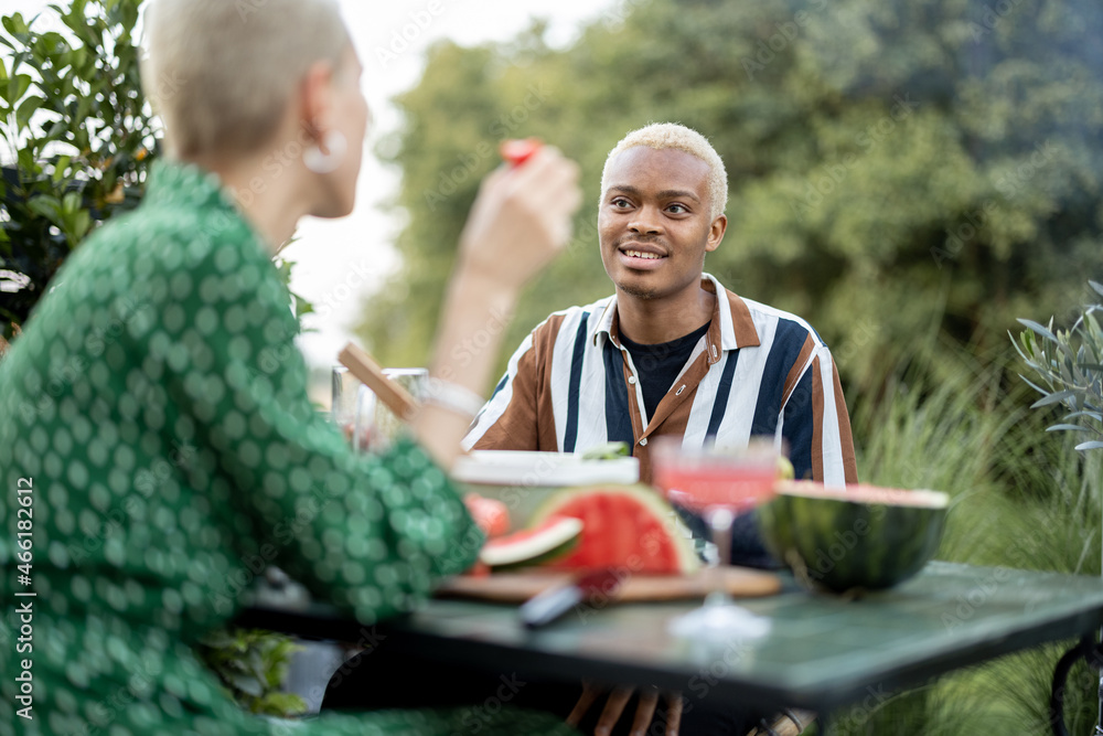 Multiracial couple having dinner at backyard of their country house on nature. Idea of healthy eatin