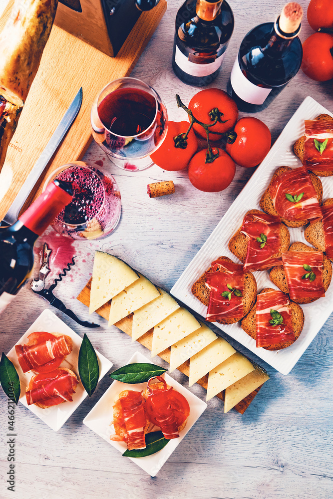 Aperitivos españoles. Aperitivos de jamón ibérico con una copa de vino, tomates maduros y queso de v