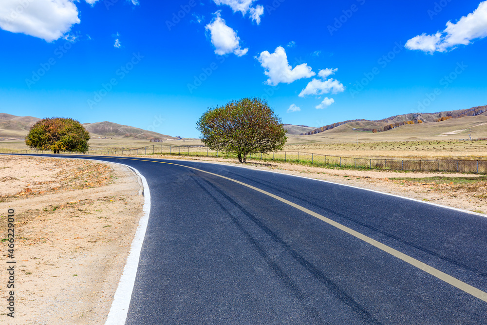 Asphalt highway and mountain scenery under blue sky.