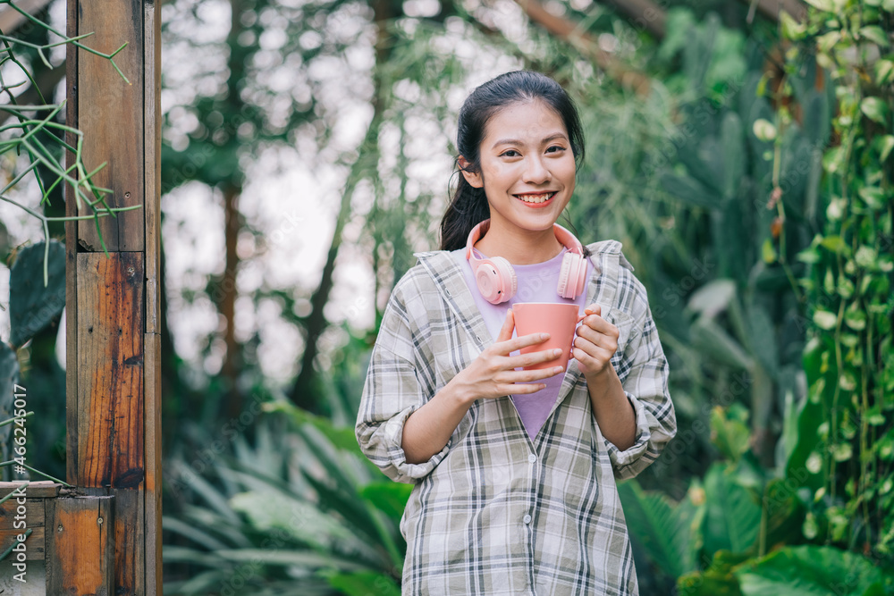 年轻的亚洲女人在花园里喝茶