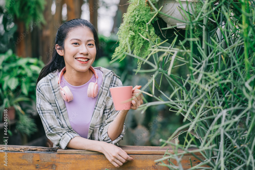 年轻的亚洲女人在花园里喝茶