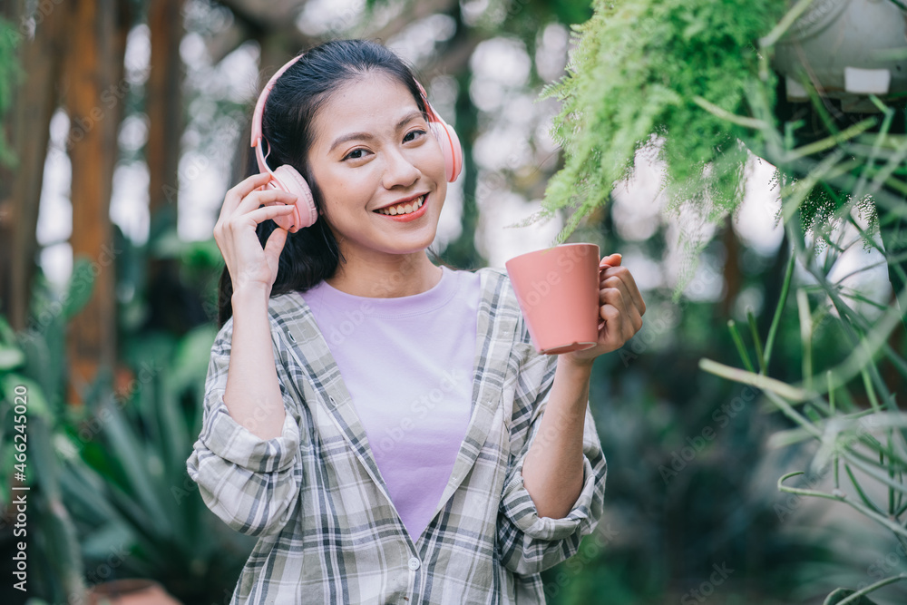 年轻的亚洲女人在花园里喝茶