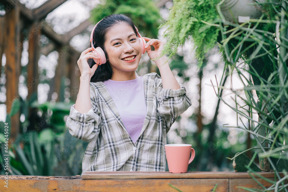 年轻的亚洲女人在花园里喝茶