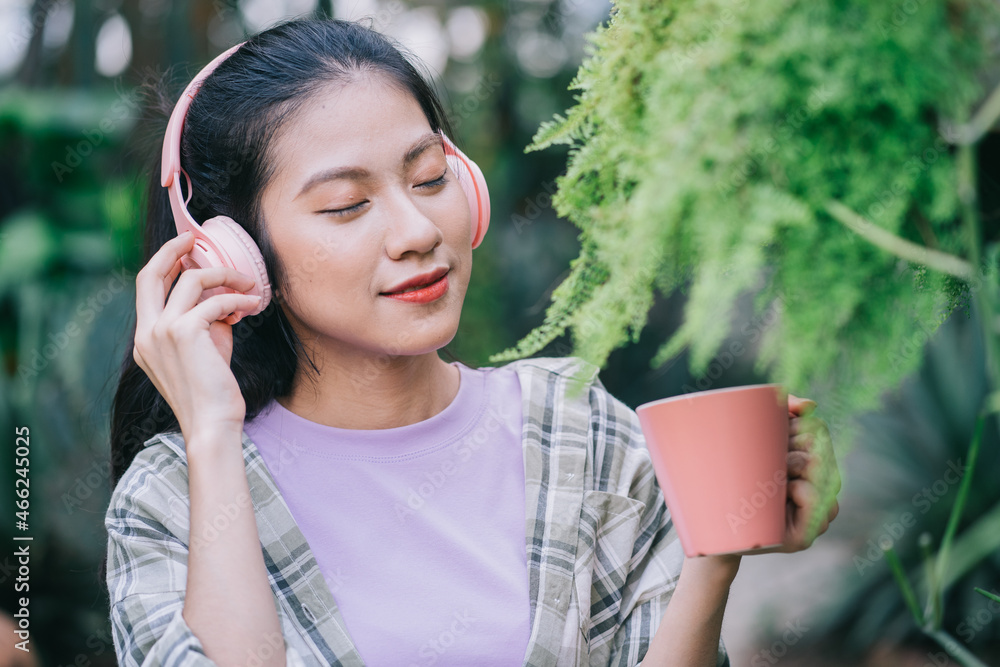 年轻的亚洲女人在花园里喝茶