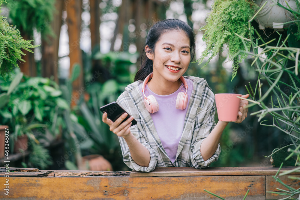 年轻的亚洲女性在花园里使用智能手机