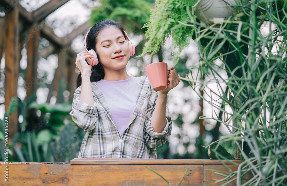 年轻的亚洲女人在花园里喝茶