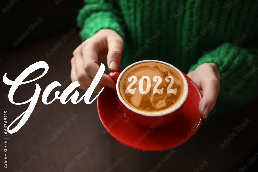 Woman with cup of tasty coffee, closeup. New Year 2022 goals