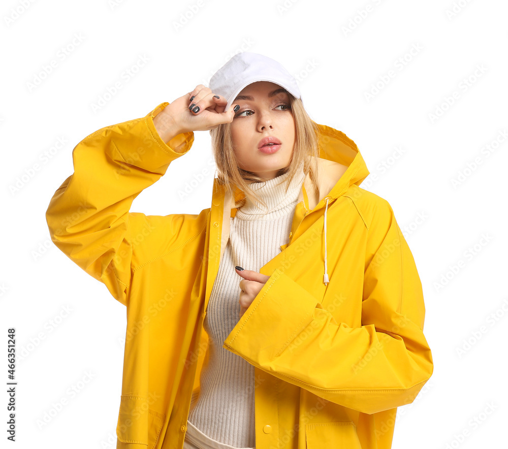 Young woman in yellow coat and baseball cap on white background