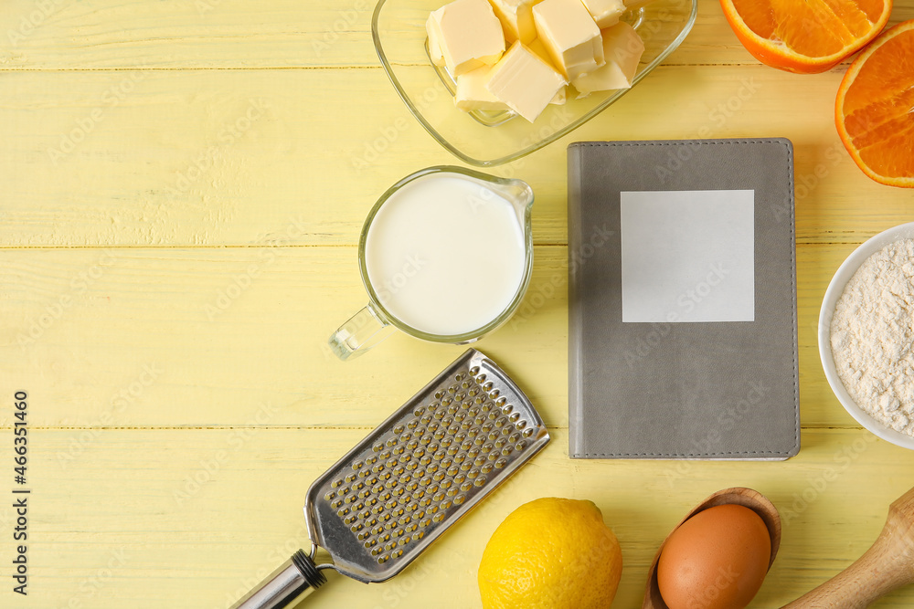 Recipe book, ingredients and kitchen utensils on color wooden background