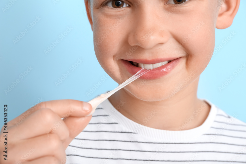 Little boy with chewing gum on blue background, closeup