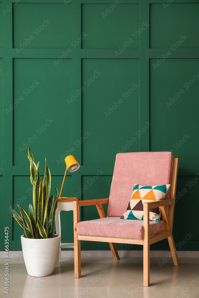 Stylish interior of living room with comfy wooden armchair and houseplant