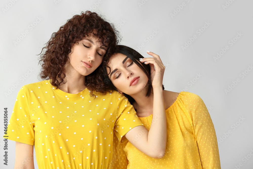 Beautiful sisters with closed eyes on grey background