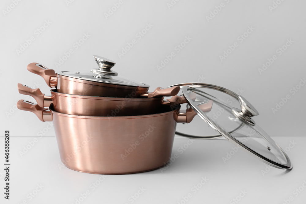 Golden cooking pots with glass lid on light background