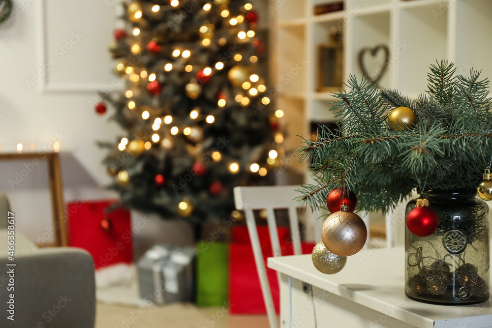 Vase with fir branches and Christmas balls on desk in room