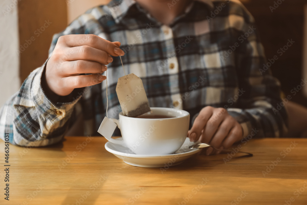 咖啡馆桌子上的女人用杯子里的袋子泡茶，特写