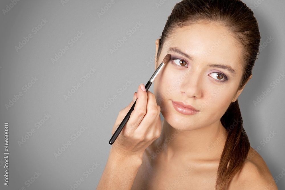 Makeup artist applies powder and blush. Beautiful woman face.