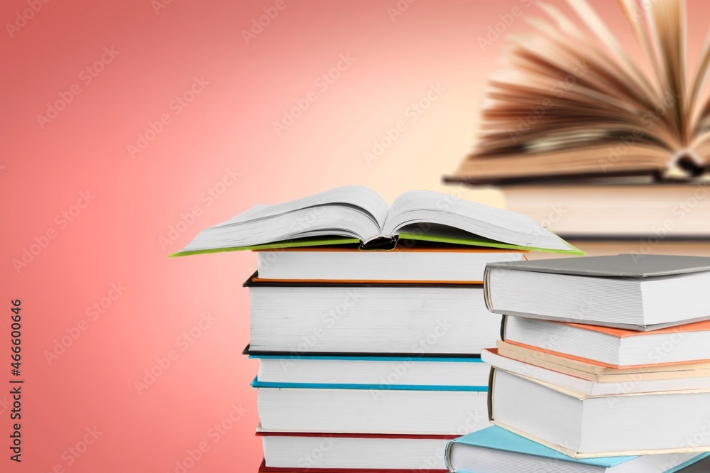 Many stacks of educational books to study in the university library on a color background