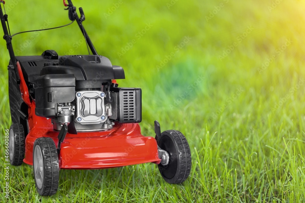 Lawn mover on green grass in modern garden. Cutting lawns.