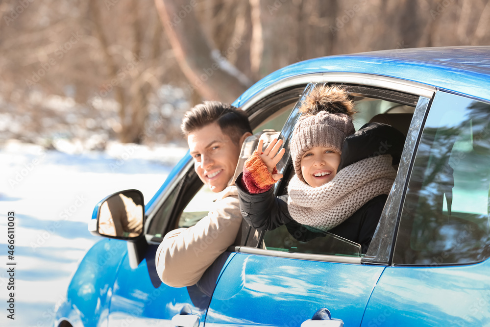 Happy father and daughter sitting in car on winter day