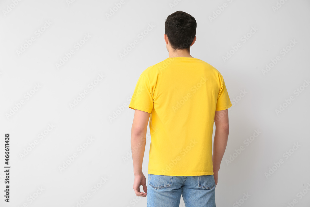 Handsome young man in stylish t-shirt on light background, back view