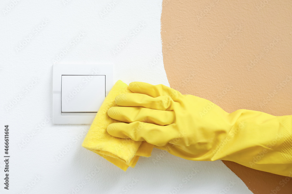 Woman wiping switch on color wall, closeup