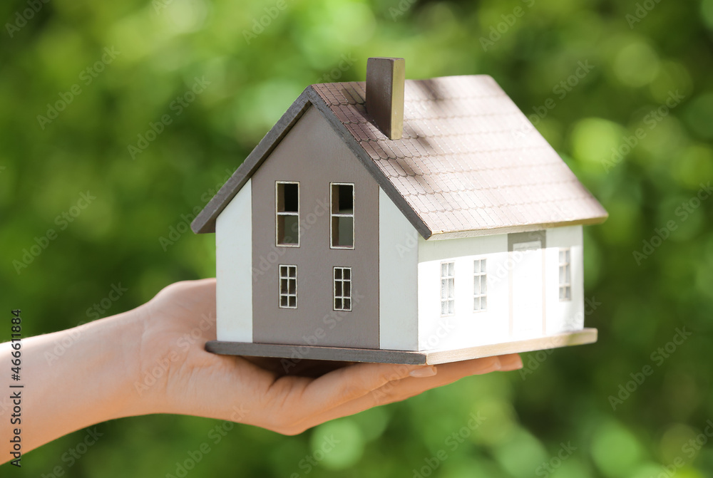 Woman with model of house outdoors, closeup