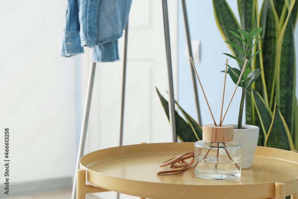 Table with eyeglasses, reed diffuser and flowerpot in modern hallway