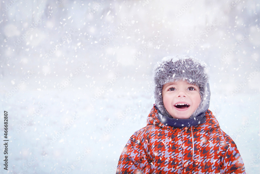 快乐的孩子享受着冬日的雪天。三岁可爱的微笑时尚潮人男孩在冬季wea