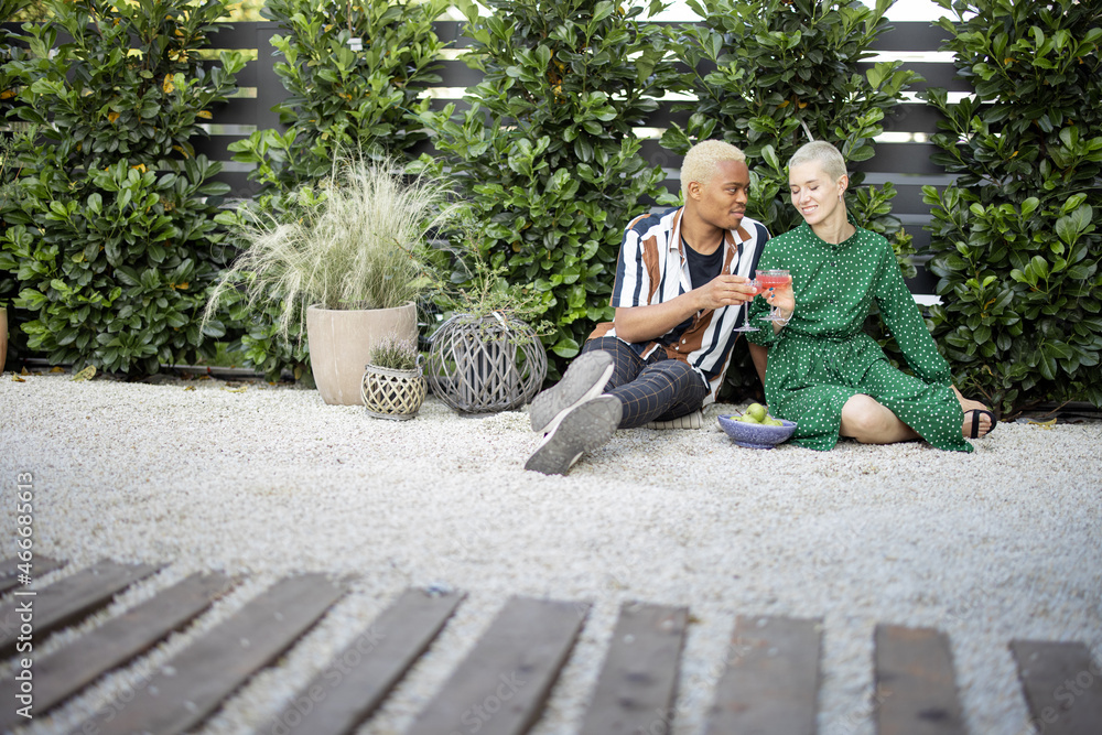 Multiracial couple drinking cocktails at home garden. European girl and black man spending time toge