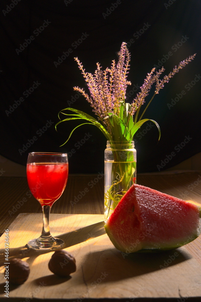 Watermelon, watermelon juice and flowers on the wooden board, black background