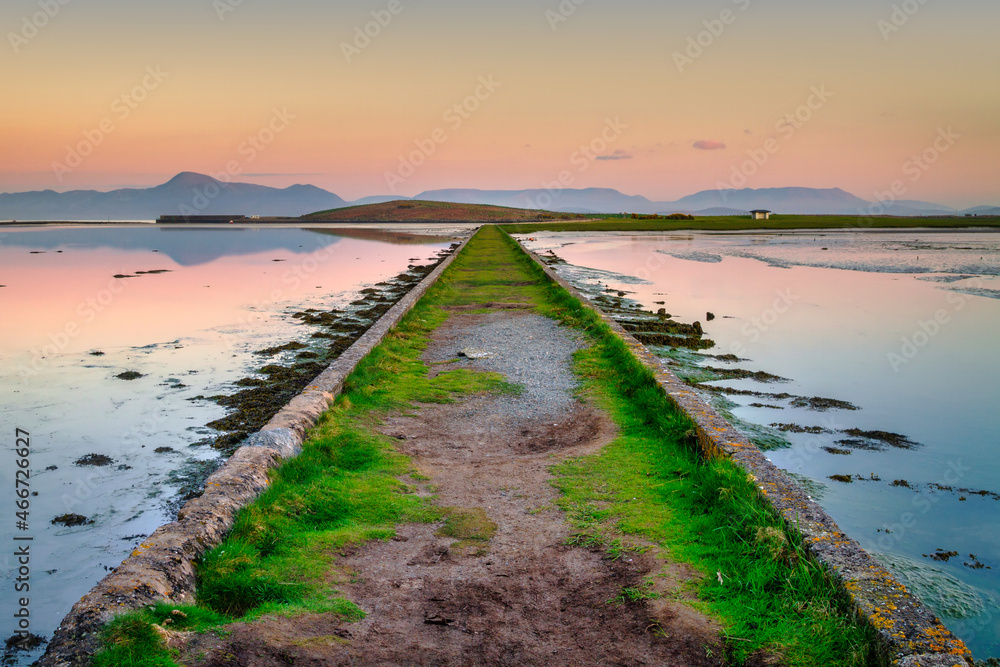 A pastel sunset over a dike with a view of the mountains. Mayo County, Ireland