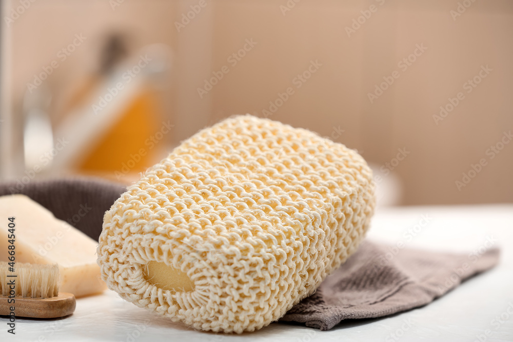 Bath sponge and towel on table in bathroom, closeup