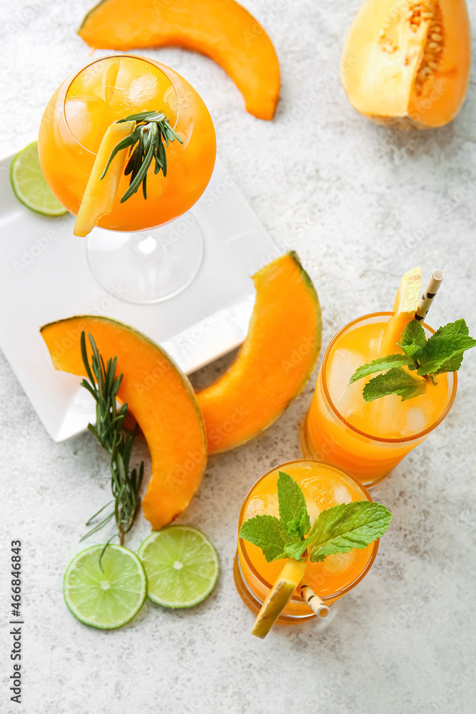 Glasses of delicious melon cocktail with mint, lime and rosemary on light background