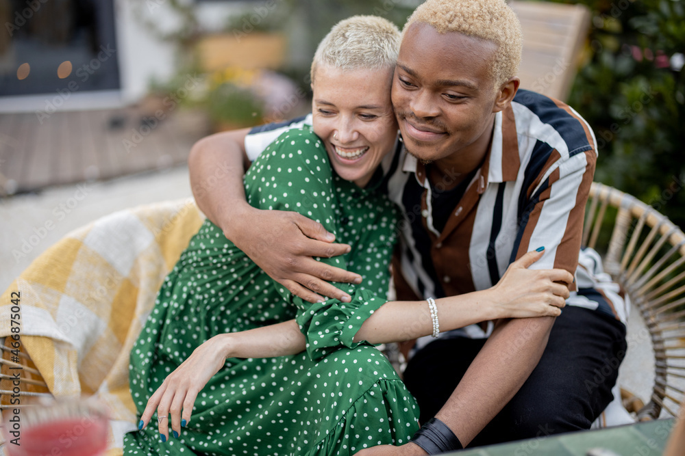 Latin man hugging his european girlfriend during a lunchtime in their garden. Joyful multiracial cou